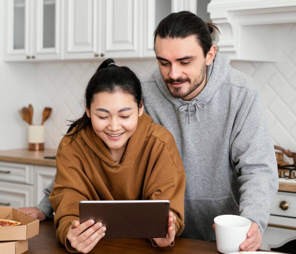 Couple taking breakfast in the kitchen and using a tablet Couple taking breakfast in the kitchen and using a tablet